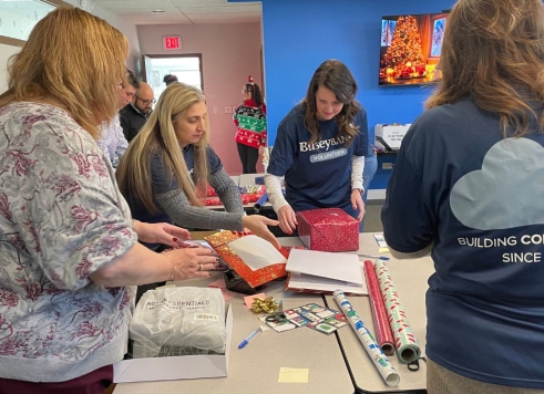 a group of people standing around a table with wrapping paper